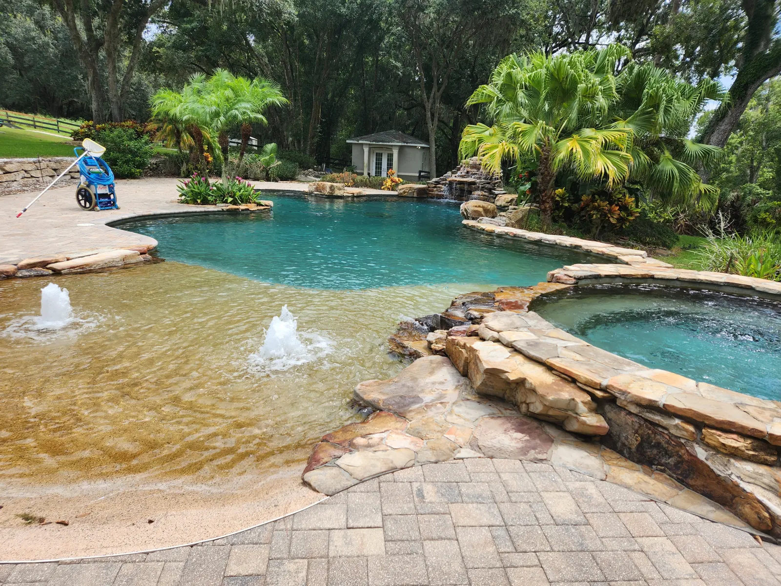 Sparkling beach-entry swimming pool with fountains and a rock-edged spa