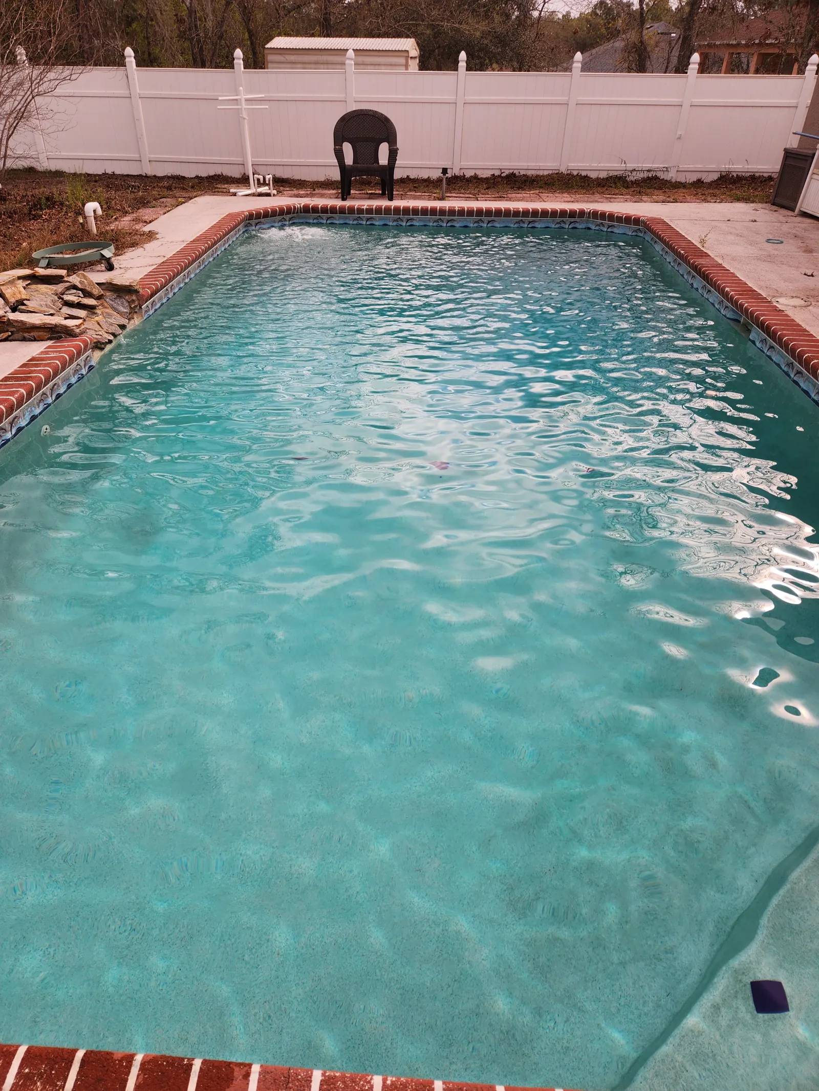 Clear pool with a brick coping and white privacy fence in Royal Highlands, Weeki Wachee