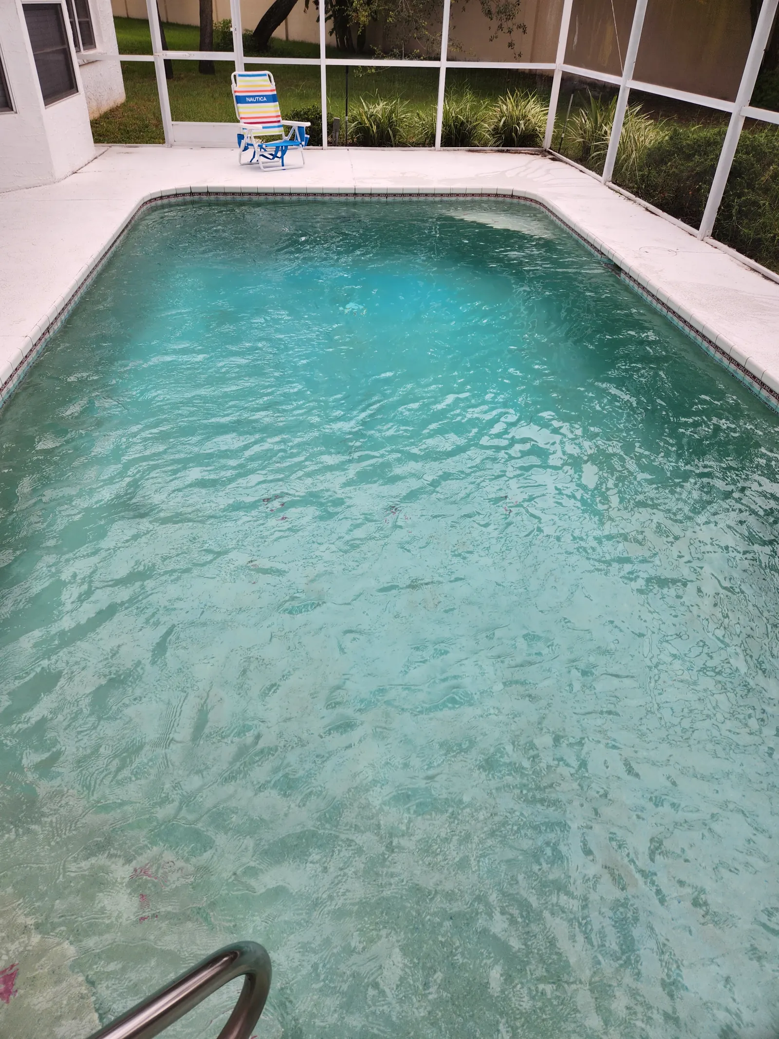 Clean rectangular pool in a screened lanai with a white deck in Timber Pines, Spring Hill